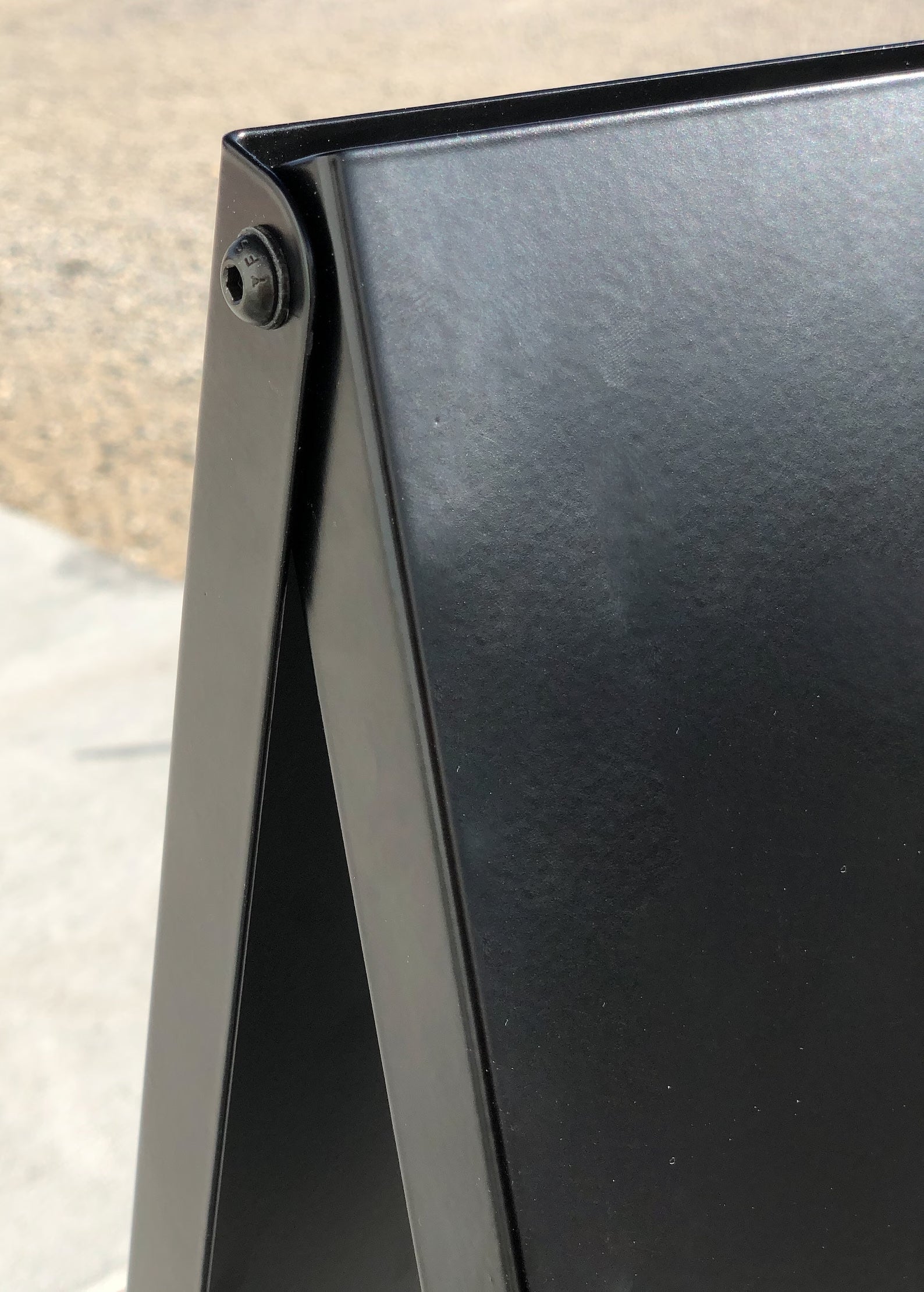 Detail image of black bolt hardware on metal custom sidewalk sign